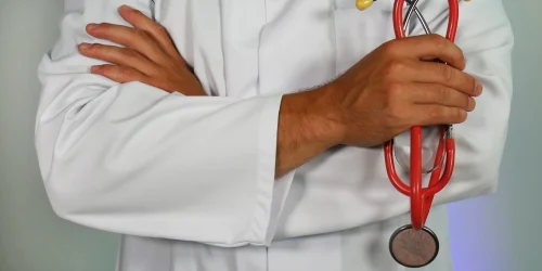 Doctor in white lab coat holding a red stethoscope.