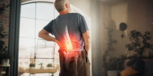 Man with visualized back pain due to spine arthritis in a living room.