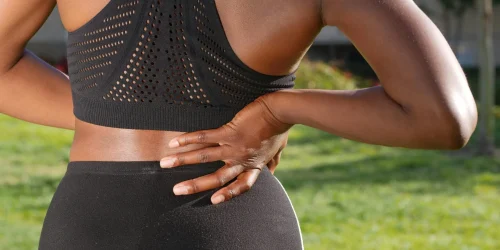 Woman clutching her lower back, possibly needing spine health treatment.