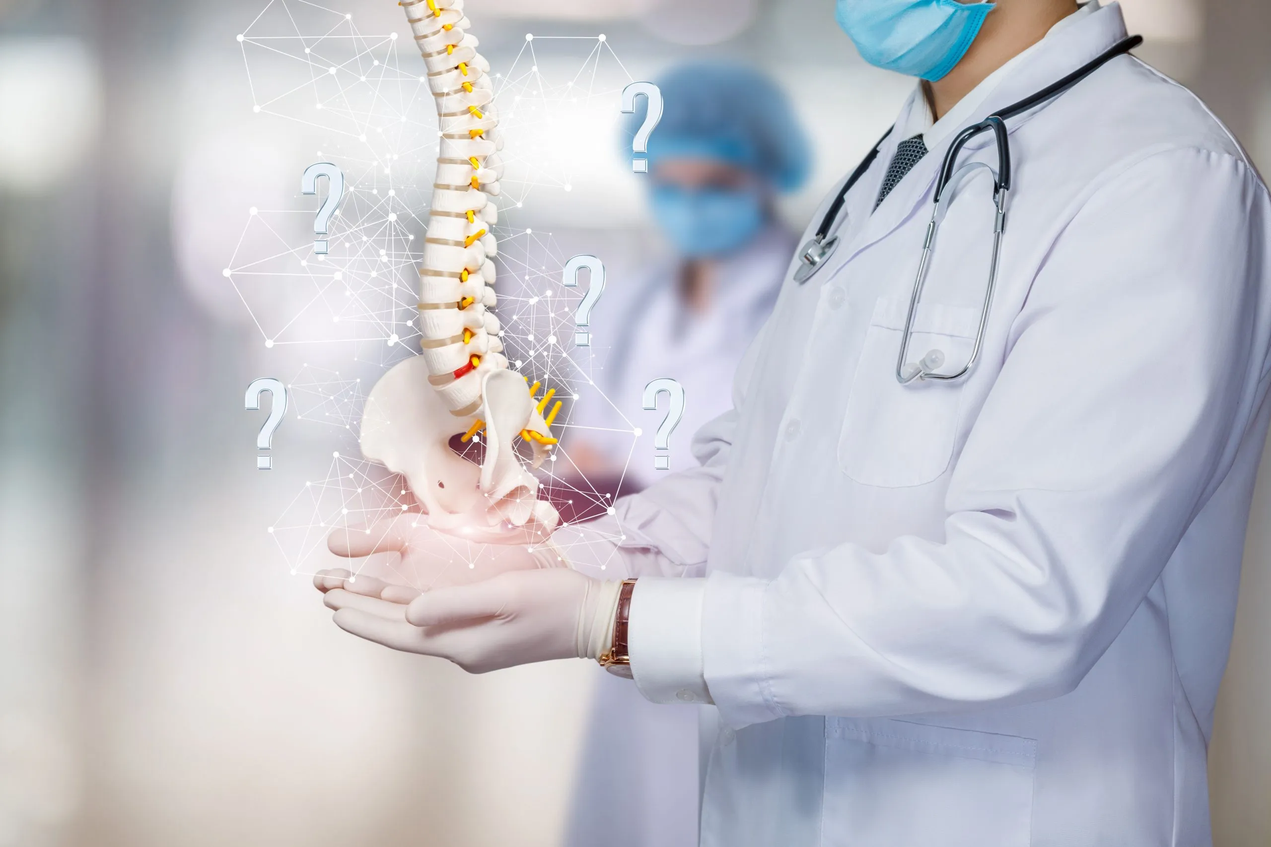 Spine surgeon holding spinal skeleton with question marks