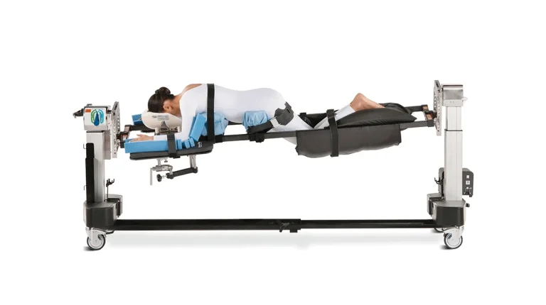 A person is strapped onto a medical positioning table in a prone position.
