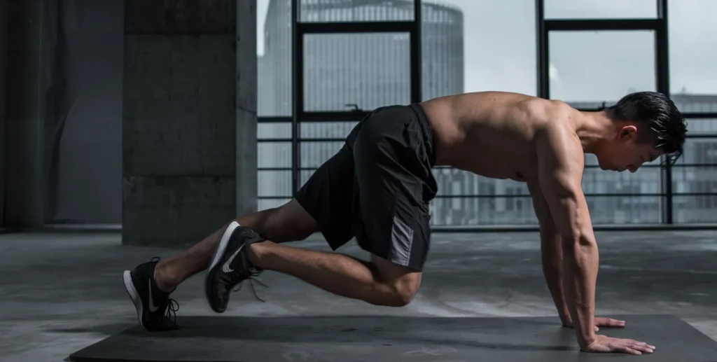 Man performing a mountain climber exercise on a gym mat.