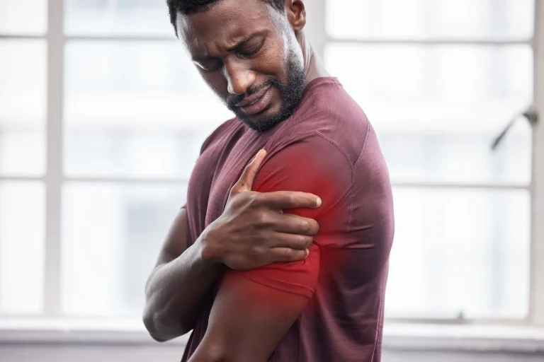 Man holding his shoulder in pain, with redness indicating discomfort.
