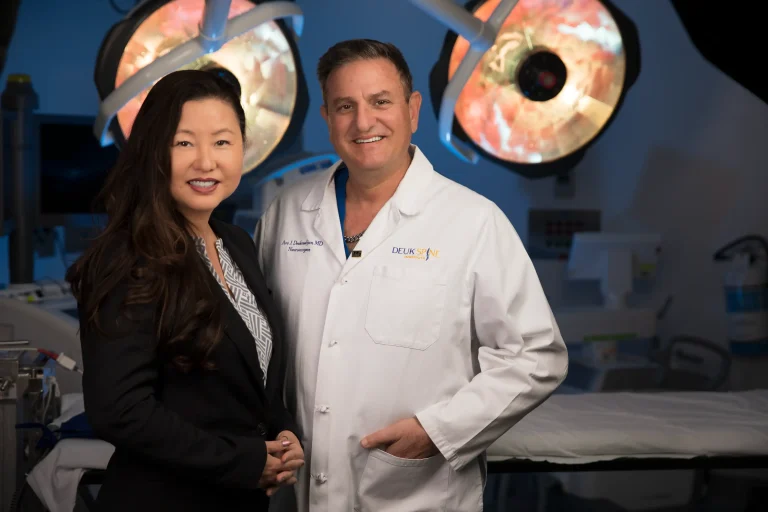 Two medical professionals smiling in an operating room setting.