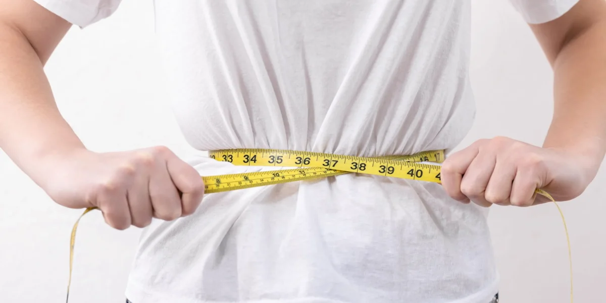 A person measuring their waist with a tape, related to herniated disc context.