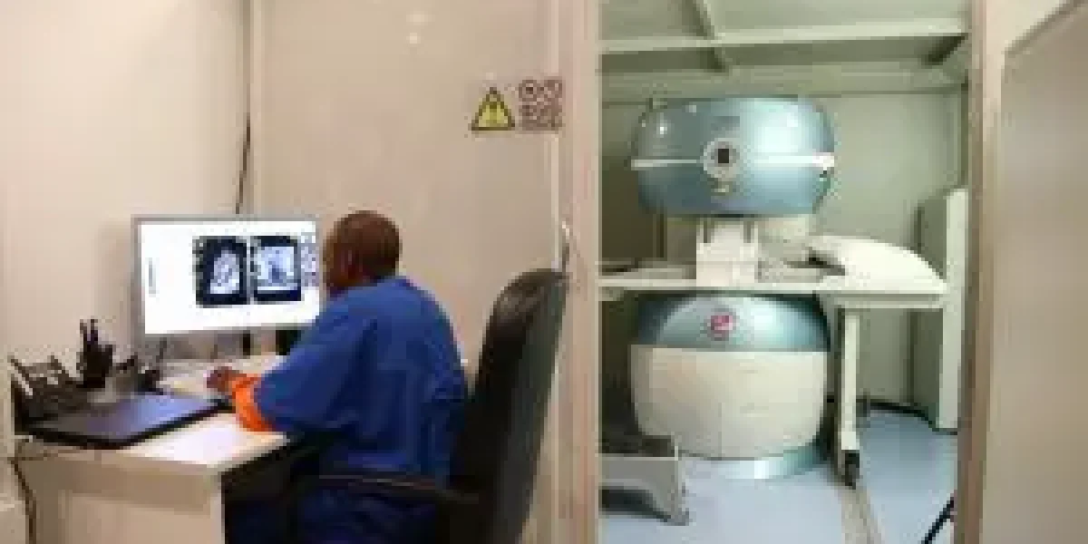 A medical professional analyzes MRI scans at a computer beside an MRI machine.