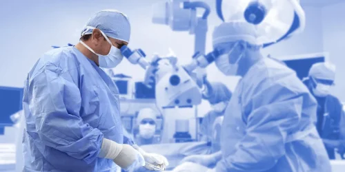 Surgeons in blue scrubs perform an operation in an operating room.